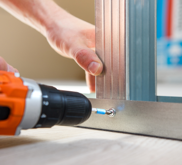 Worker attaching aluminum pieces with a drill